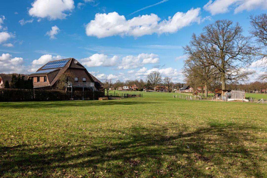 Wohnhaus mit grossem Walmdach am Ortsrand, auf der Südseite eine Modulfläche, davor eine Wiese.