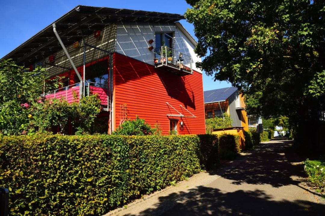 Moderne Wohnhäuser mit Modulen sowohl auf dem Dach als auch an der Fassade, aufgenommen von der Zufahrt aus.